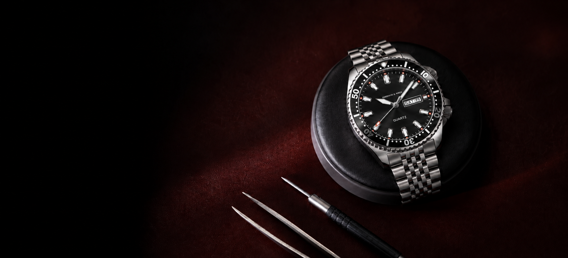 Harrison & Wren black dial stainless steel watch on a watchmaker’s bench